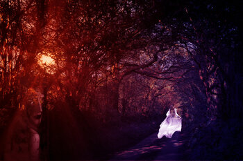 A forest toned in red to purple, with a white-clad woman in the background running ... probably away from the ghost in the foreground.