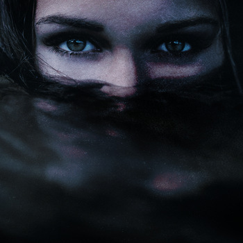 A dark image of a woman in water, with barely her eyes above the surface.