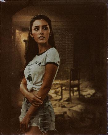 In front of the same room as the ghost Erik, stands a woman looking more than a little nervous. She's pretty, in jean shorts and a t-shirt, with her dark hair loose. St Dymphna.